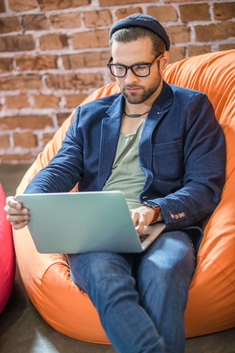 handsome-man-working-on-laptop-while-sitting-in-be-UBPGGBW-small